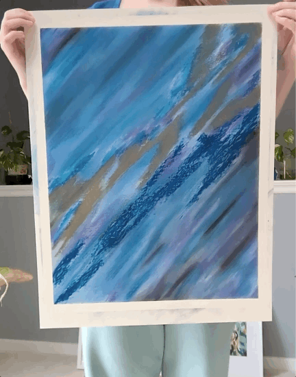 artist holding a large blue oil pastel artwork